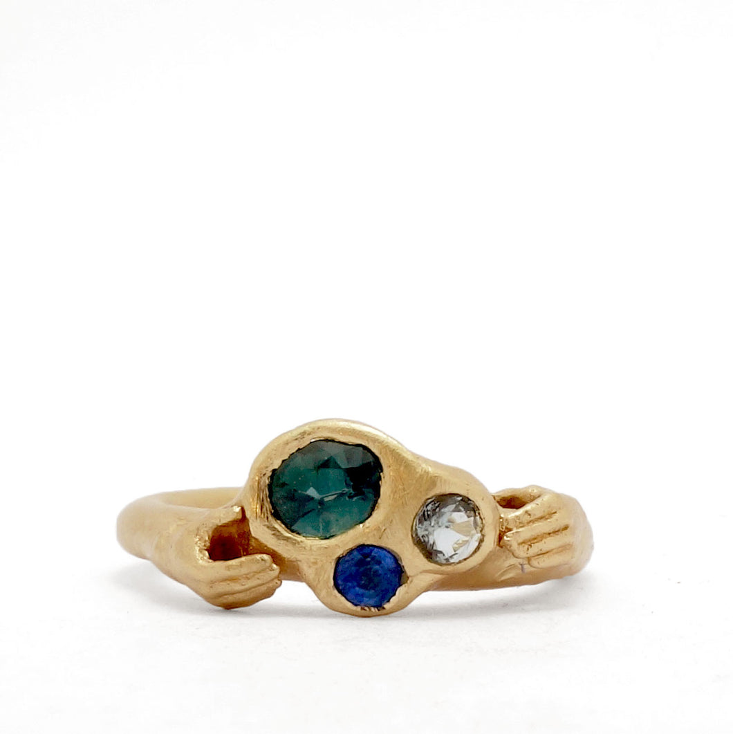 Fraser Hamilton Jewellery | 'Set' Alternative Engagement Ring with diamond and sapphires held in yellow gold with two detailed hands similar to a Claddagh ring